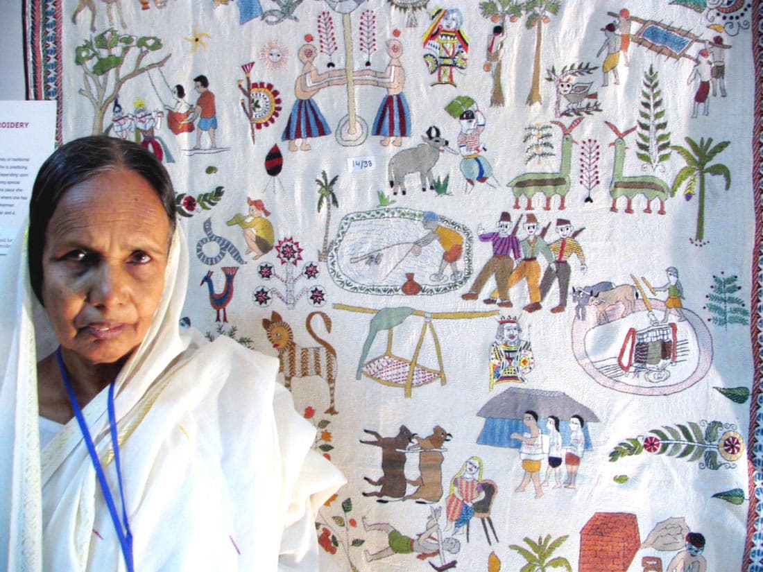 Kantha artisan Lobihar Banu beside an embroidered narrative textile