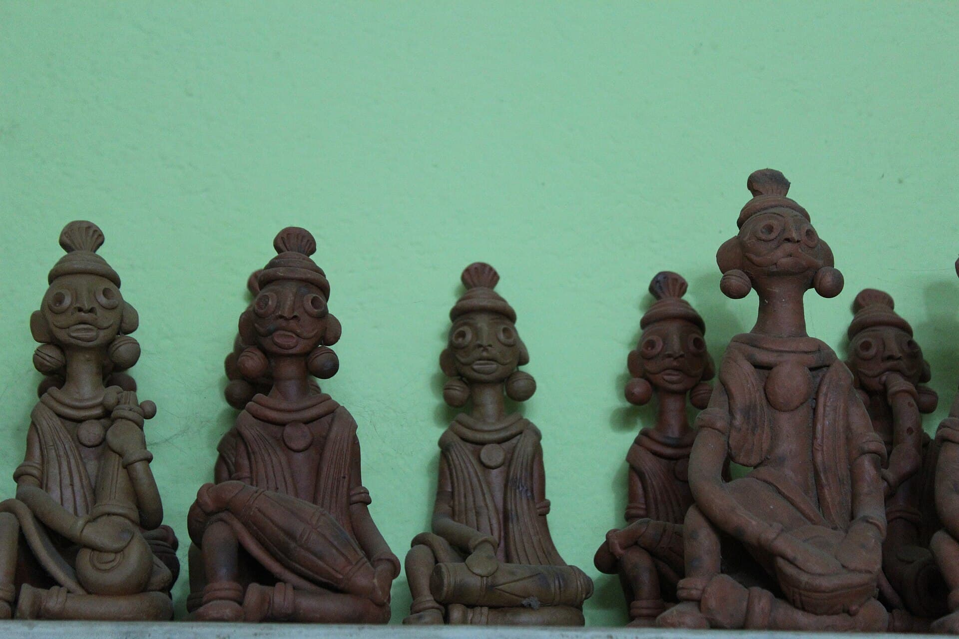 Panchmura terracotta figures arranged against a green wall